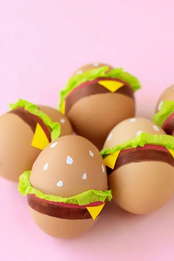 six eggs decorated like hamburgers sitting on top of each other in front of a white background