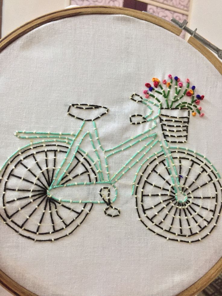 a cross stitch bicycle with flowers in the basket on it's handlebars