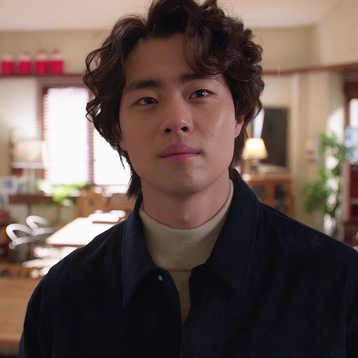 a young man standing in front of a dining room table and looking at the camera