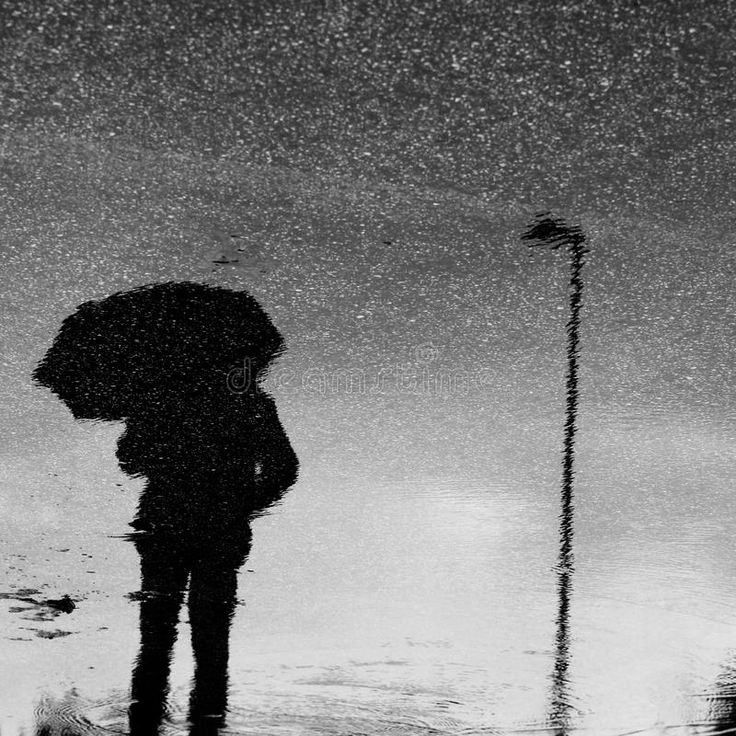 a person standing in the rain with an umbrella over their head, and it is raining