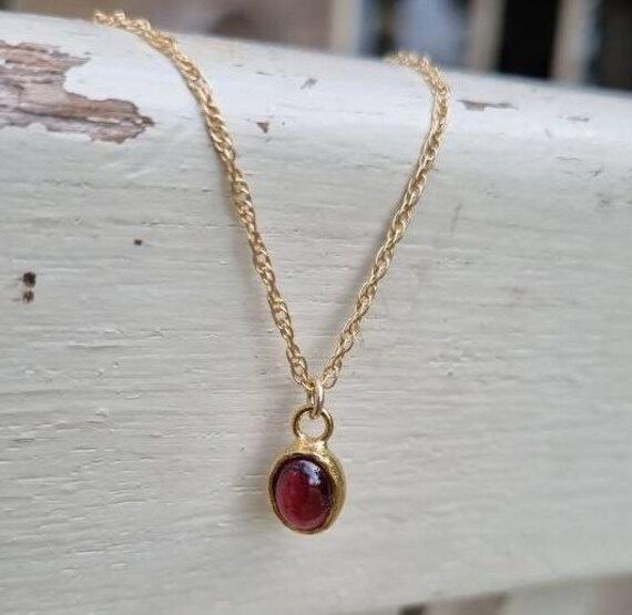 Gold Garnet necklace, 14k gold pendant necklace, January birthstone necklace mom, Red Garnet necklace, January Birthday, Gold Garnet Jewelry This minimalist Garnet necklace was set with a deep red January birthstone pendant, to beautifully accompany you through your busy days. The classic design is always pretty for day and evening, work or fun. The Red oval necklace is handmade and delicate and is just a great January birthstone necklace and the perfect chic and elegant gift. Dimensions: Oval pendant length is 1 cm (0.4") and 8mm (0.3") wide. The Garnet is 6x8mm This pendant necklace is available in multiple lengths.  Materials: 14k gold filled chain 6X8mm oval Garnet cabochon cut. The pendant necklace is available in 14k gold plated brass. It is also available in 9k or 14k solid gold. Pl Dainty Red Round Pendant Necklace, Red Dainty Birthstone Jewelry, Dainty Red Birthstone Jewelry, Red Jewelry With Bezel Setting For Gift, Red Round Pendant Jewelry For Mother's Day, Red Birthstone Necklace In 14k Gold, Gold Oval Pendant Birthstone Necklace As Gift, Red Birthstone Round Pendant Jewelry, Gift Yellow Gold Birthstone Necklace With Bezel Setting