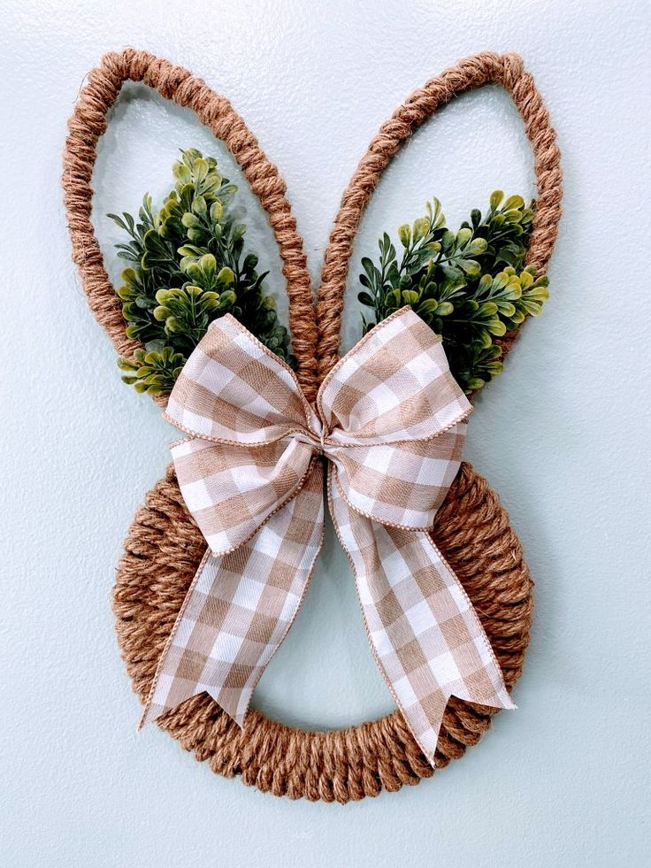 an easter bunny shaped wreath hanging on the wall with a bow and greenery attached to it