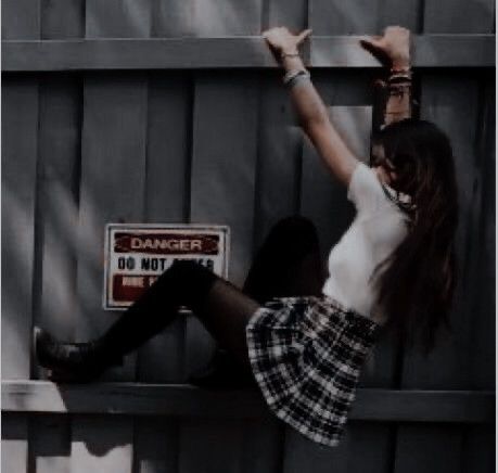 a woman is leaning against a fence with her arms in the air