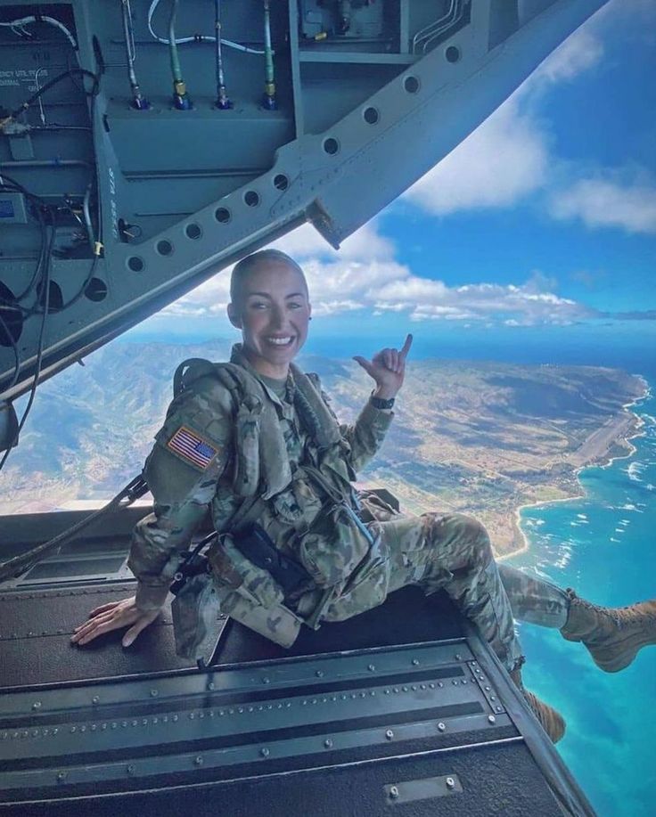 a woman is sitting in the cockpit of an airplane and smiling at the camera with her hand up