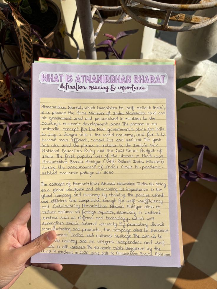 a person holding up a paper with writing on it in front of a potted plant