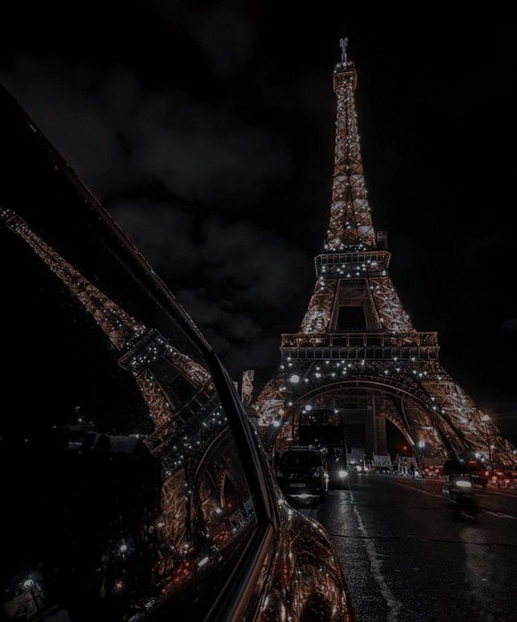 the eiffel tower is lit up at night with lights on it's sides