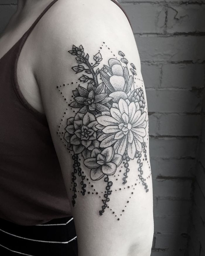 a black and white photo of a woman's arm with flowers tattooed on it