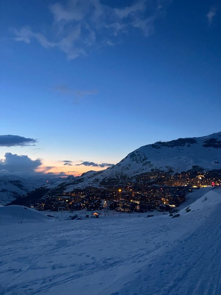 a person on skis is standing in the snow at night with city lights behind them