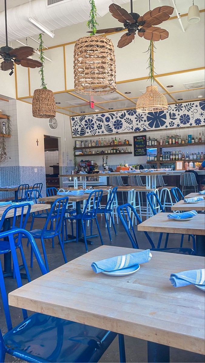 blue chairs and tables in a restaurant with ceiling fan lights above the bar area,