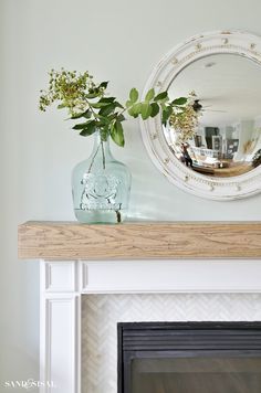 a fireplace with a mirror above it and vases on top of the mantel