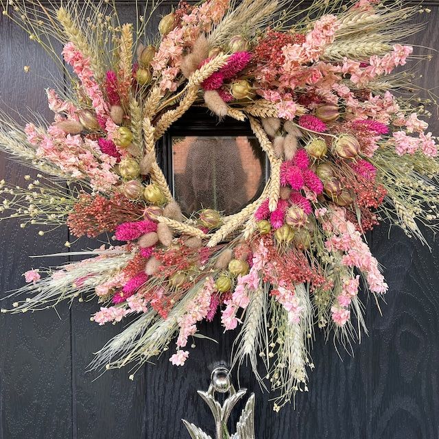 a wreath is hanging on the door with pink and green flowers in it's center