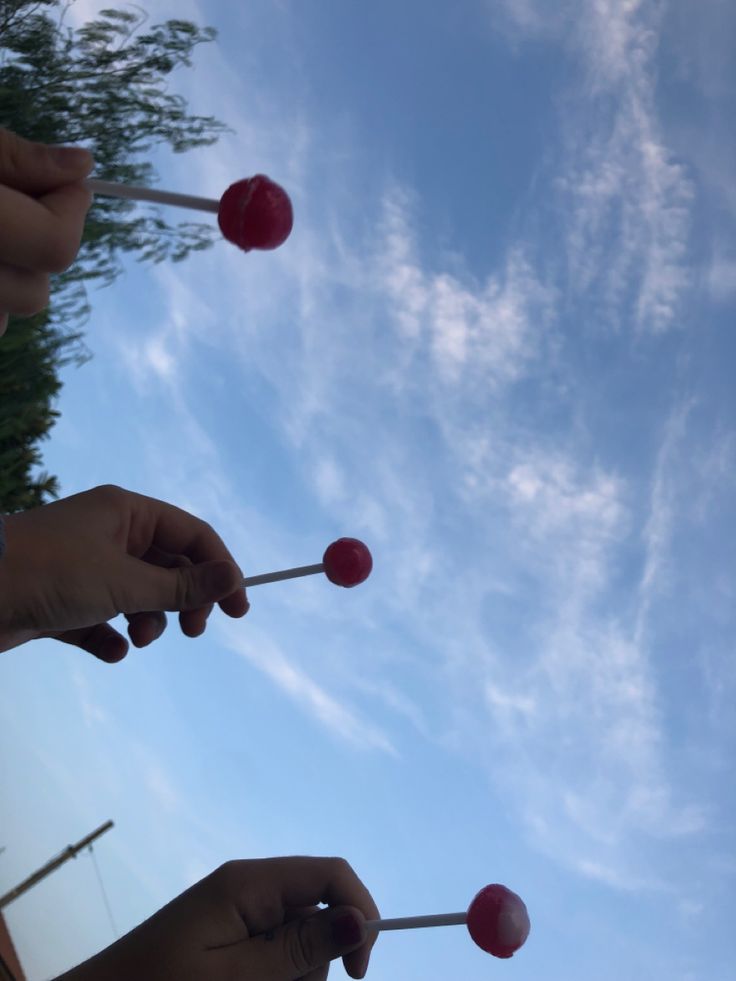 two people holding candy lollipops in their hands with the sky behind them