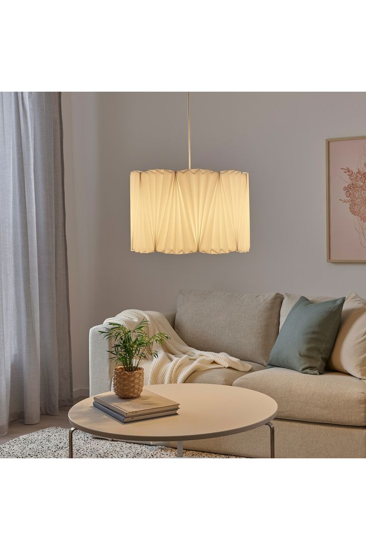 a living room with a couch, coffee table and lamp hanging from the ceiling above it