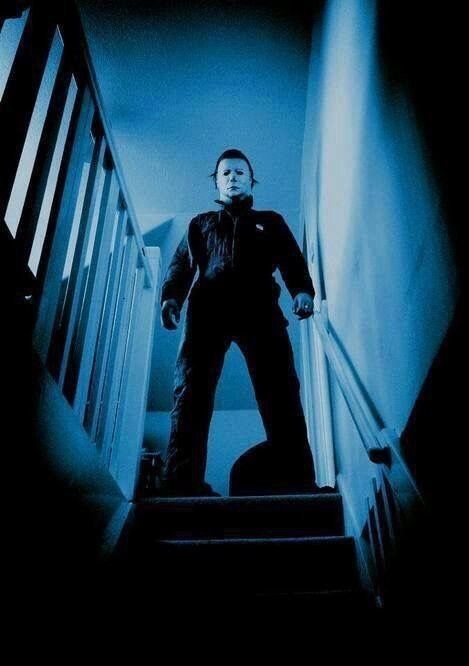 a man standing at the top of stairs in front of a stair case with blue light coming from behind him