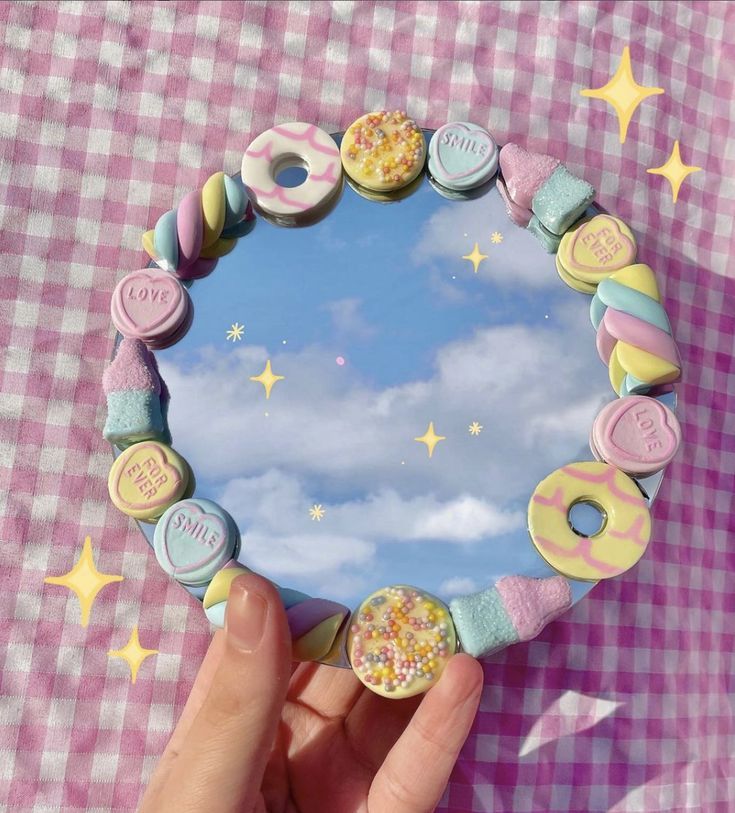 a hand holding a mirror with doughnuts on it