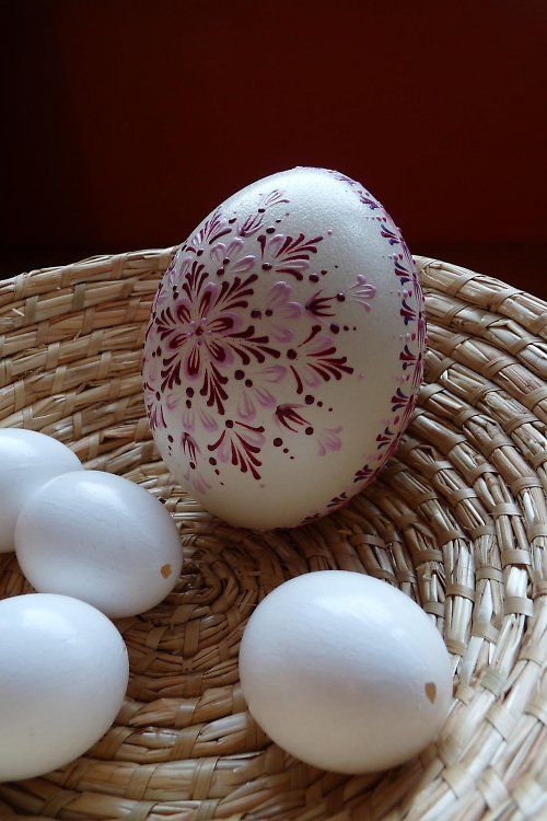 an egg sitting on top of a wicker basket next to five eggs in it