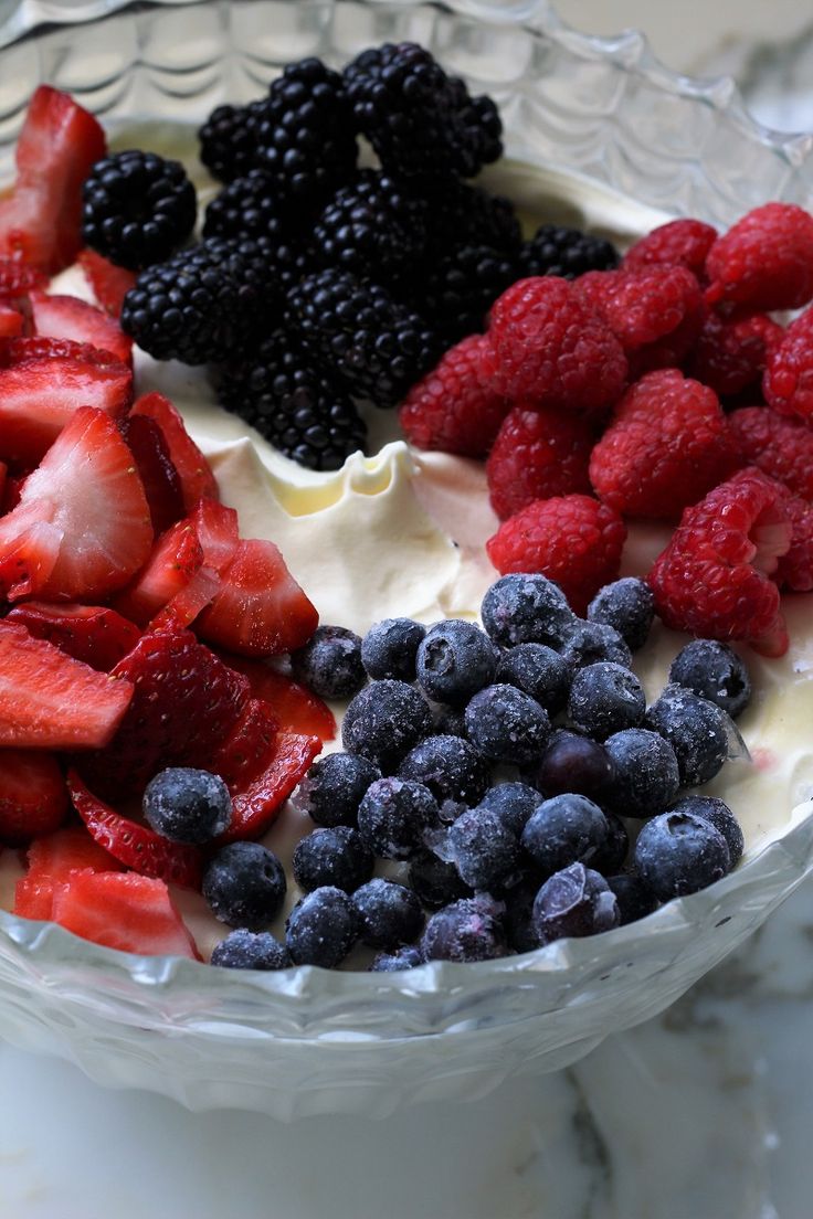 berries, strawberries, and blueberries are arranged in a bowl on a marble surface