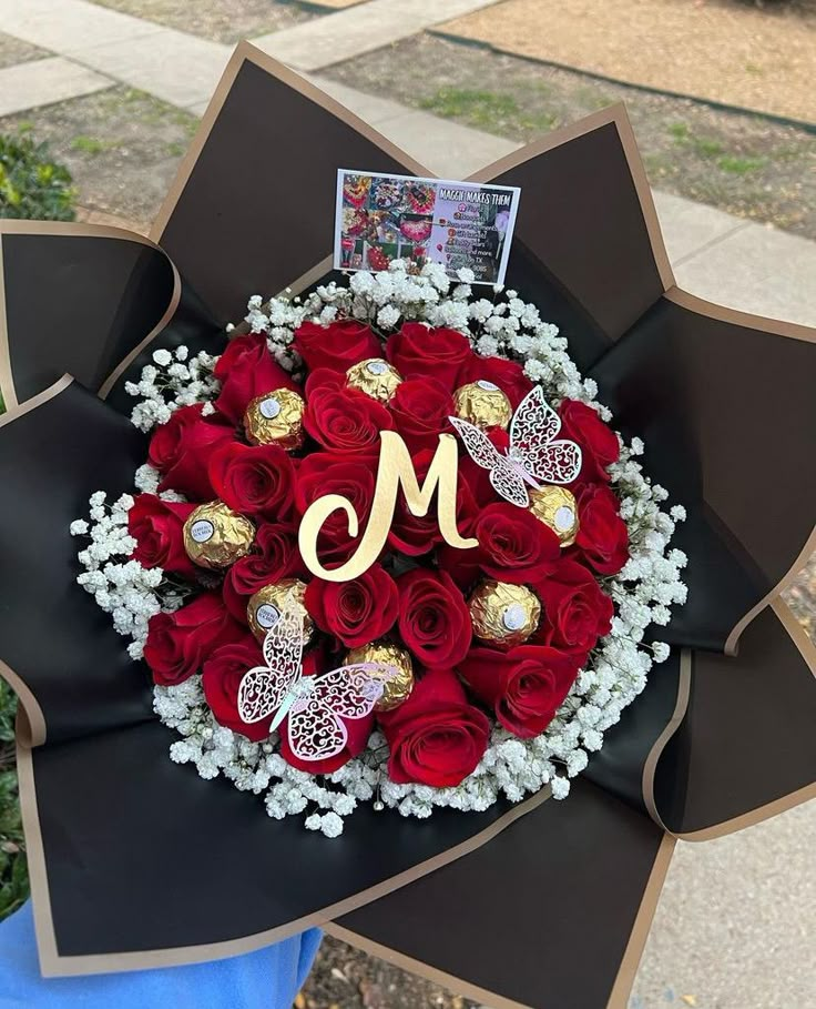 a bouquet of red roses in the shape of a heart with a monogram on it