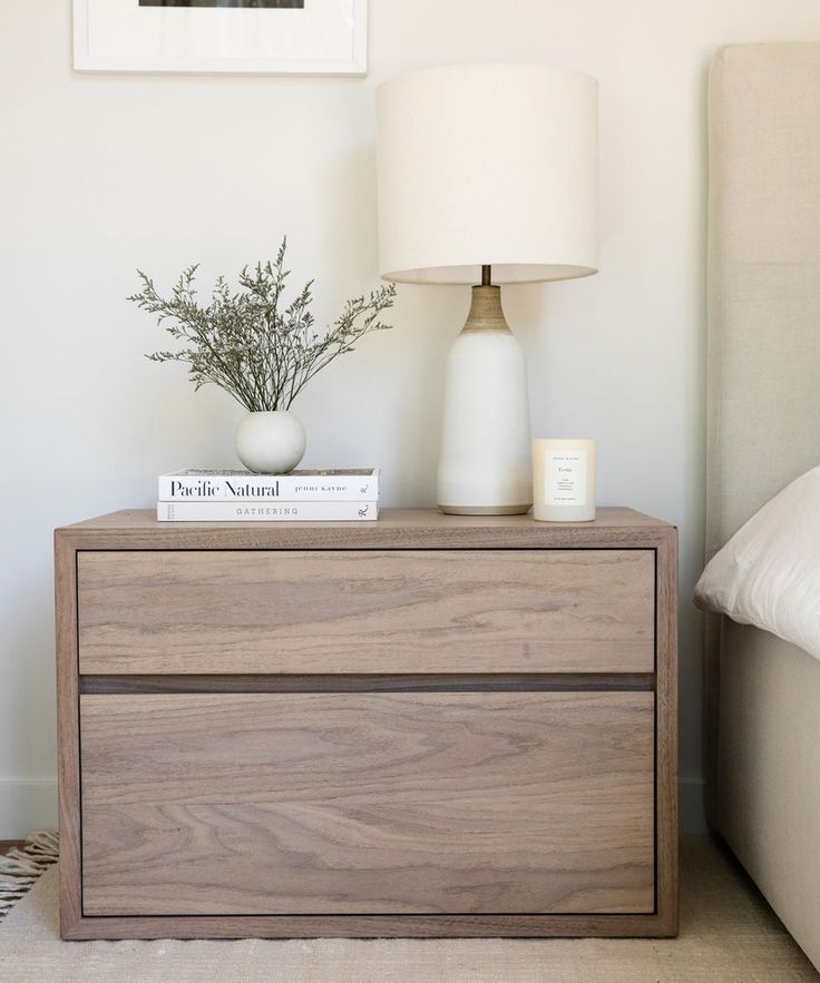 a nightstand with a book and vase on it