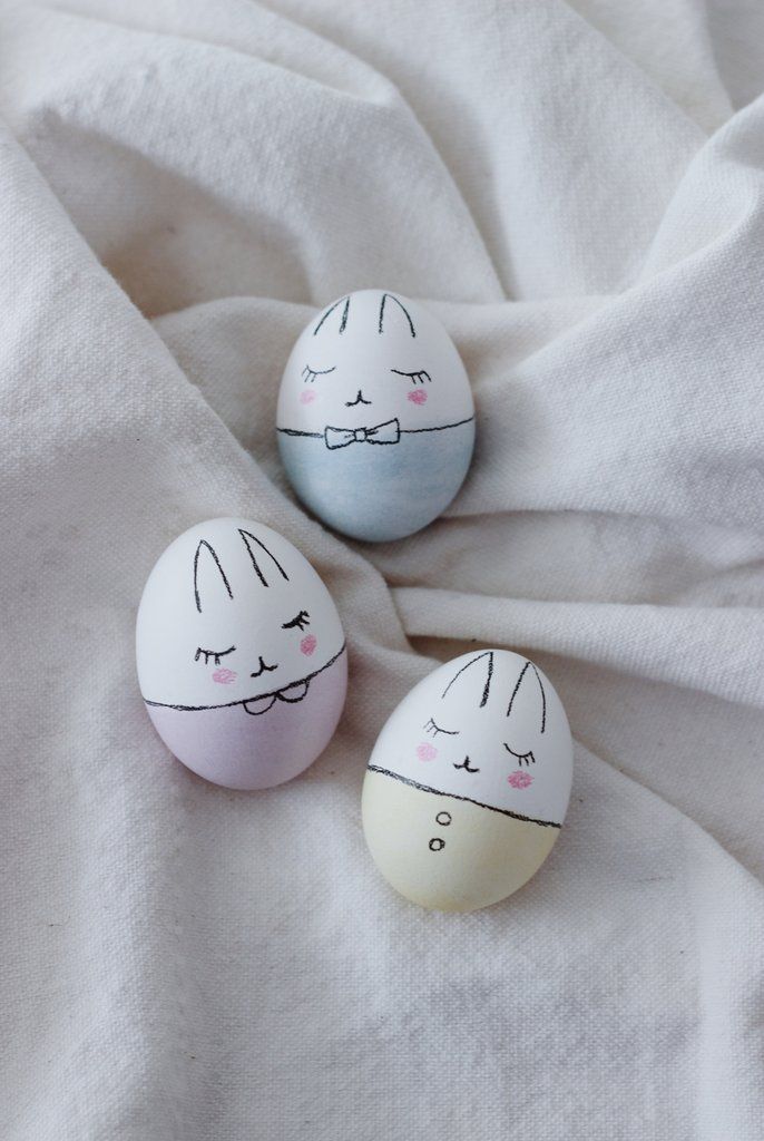 two painted eggs sitting on top of a white sheet