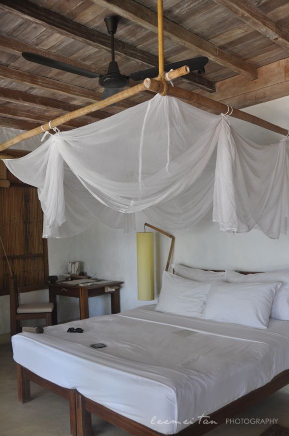 a bed with white sheets and pillows in a room that has wood beams on the ceiling