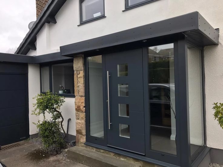 a house that has some doors and windows on the side of it with plants in front