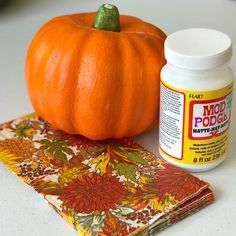 an orange pumpkin sitting on top of a table next to a jar of food coloring