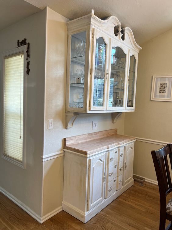 an empty kitchen with white cabinets and wood flooring on the hardwood floors, along with a dining room table and chairs