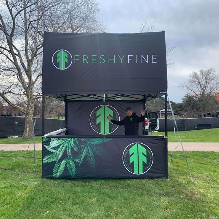 a man standing in front of a tent that says freshy fine on the side