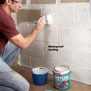 a man is painting a brick wall with white paint