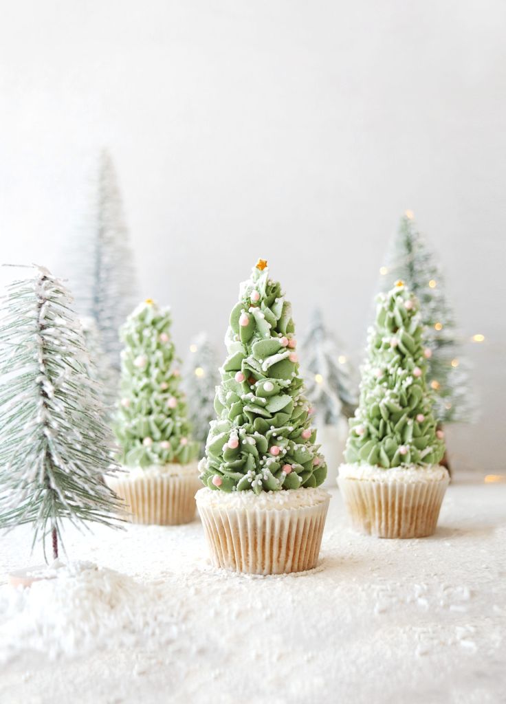 cupcakes with frosting and christmas trees on them are sitting in the snow