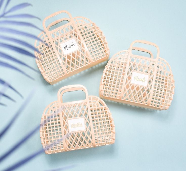 three pink plastic purses sitting next to each other on a blue surface with palm leaves in the background