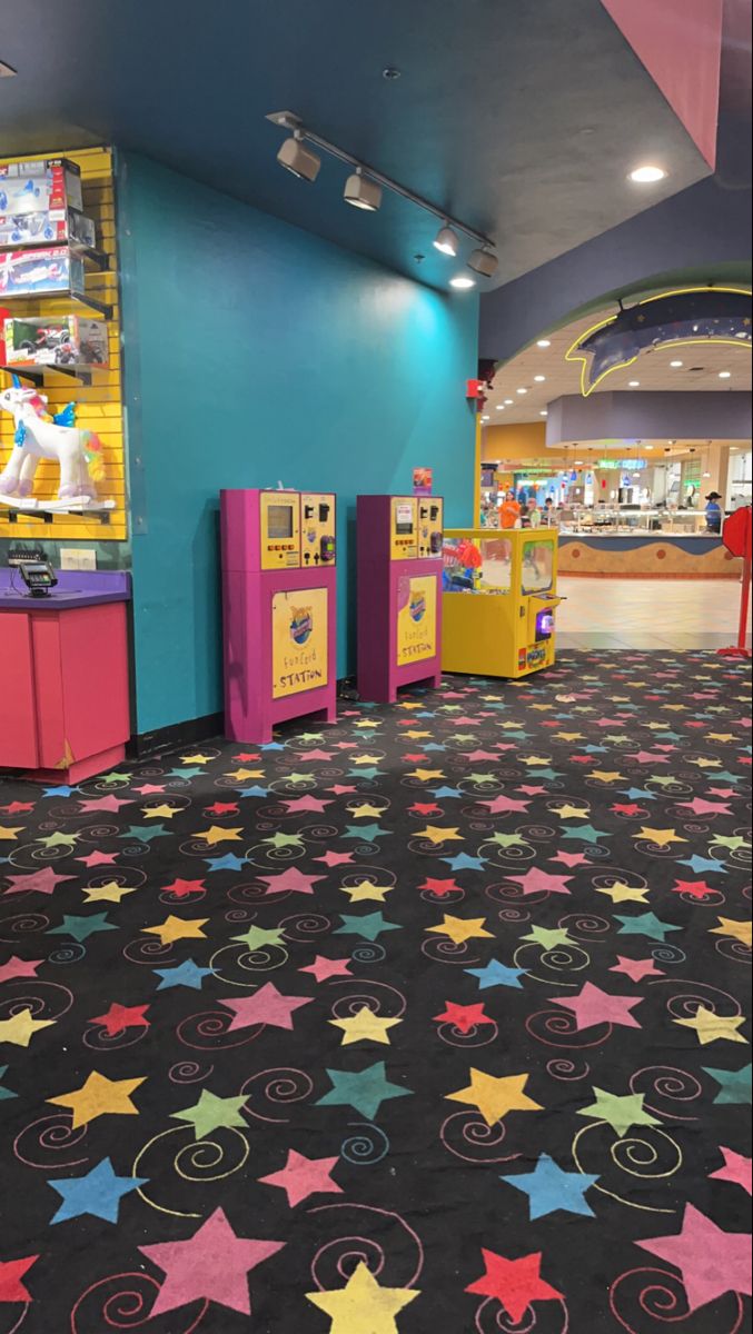 an indoor play area with brightly colored stars on the floor and arcade machines in the background