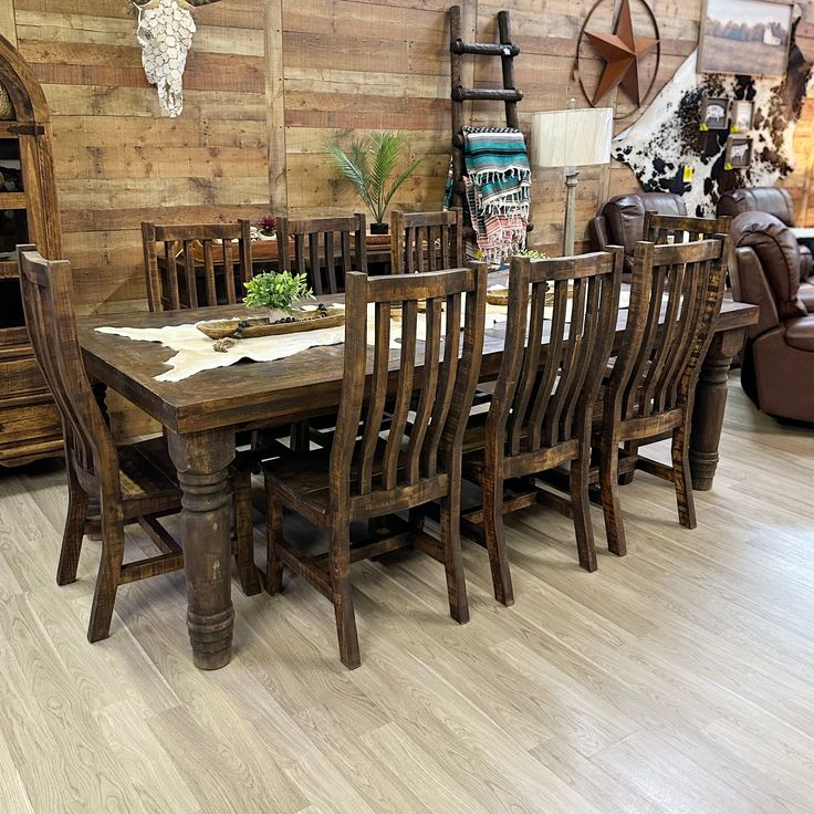 a dining room table and chairs in front of a wooden wall with deer heads on it