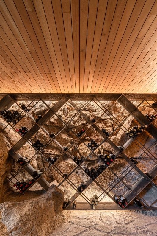 a wooden ceiling with many wine bottles on the wall and in front of it is a stone staircase