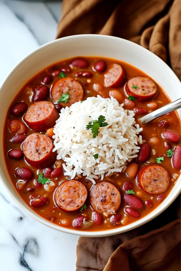 a white bowl filled with beans and rice next to a brown napkin on top of a table