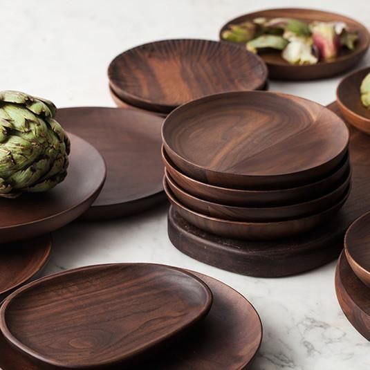 a bunch of wooden plates stacked on top of each other next to an artichoke