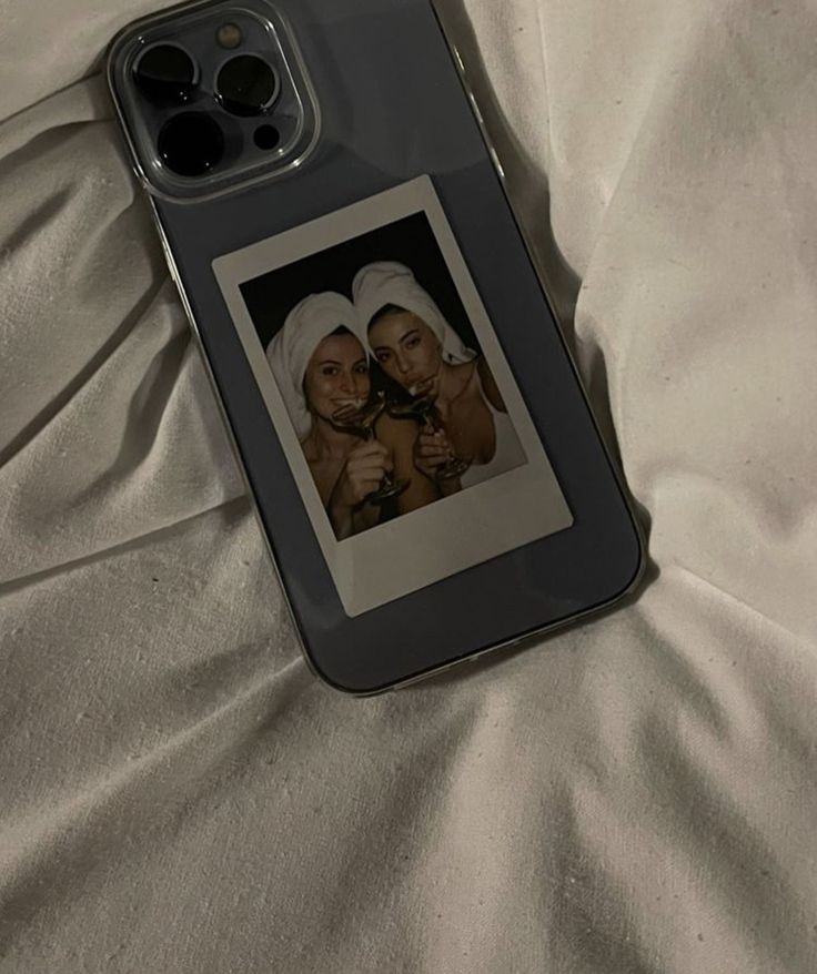 an iphone case with two women on it laying on a white bed sheet next to each other