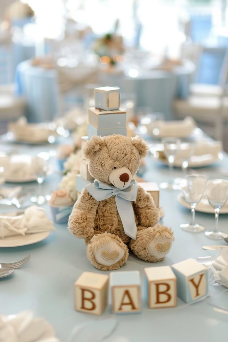 a teddy bear sitting on top of a table with baby block letters in front of it