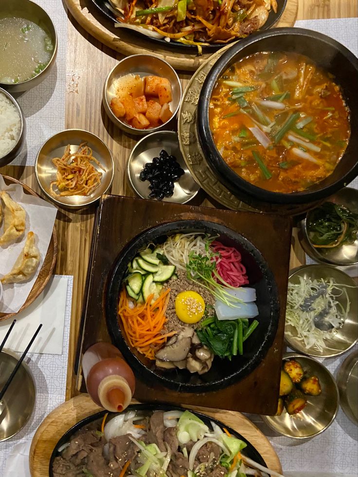 a table topped with bowls filled with different types of food next to plates and utensils