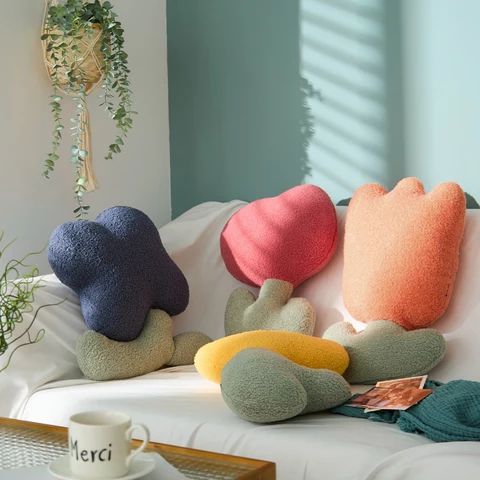 four different colored pillows sitting on top of a white couch next to a coffee cup