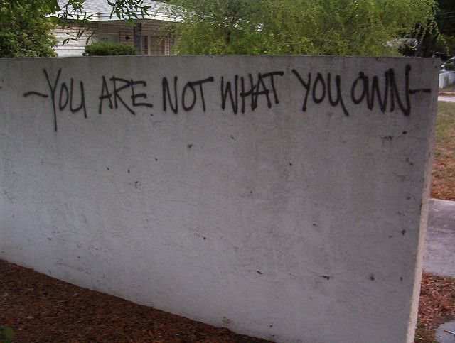 graffiti written on the side of a wall that says, you are not what you own