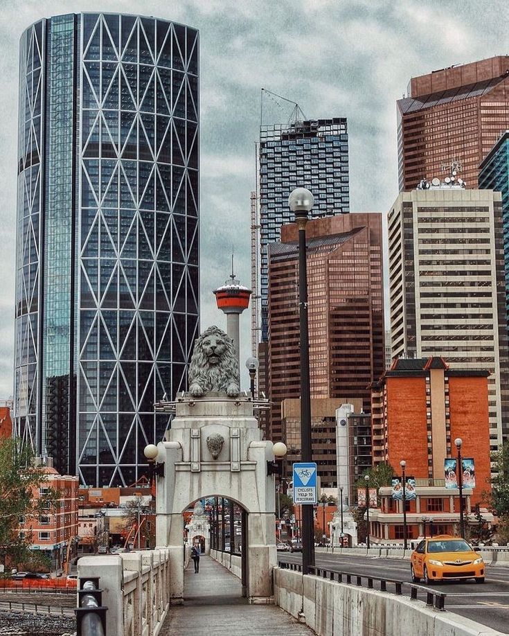 a bridge with a lion statue on it in front of some tall buildings and traffic