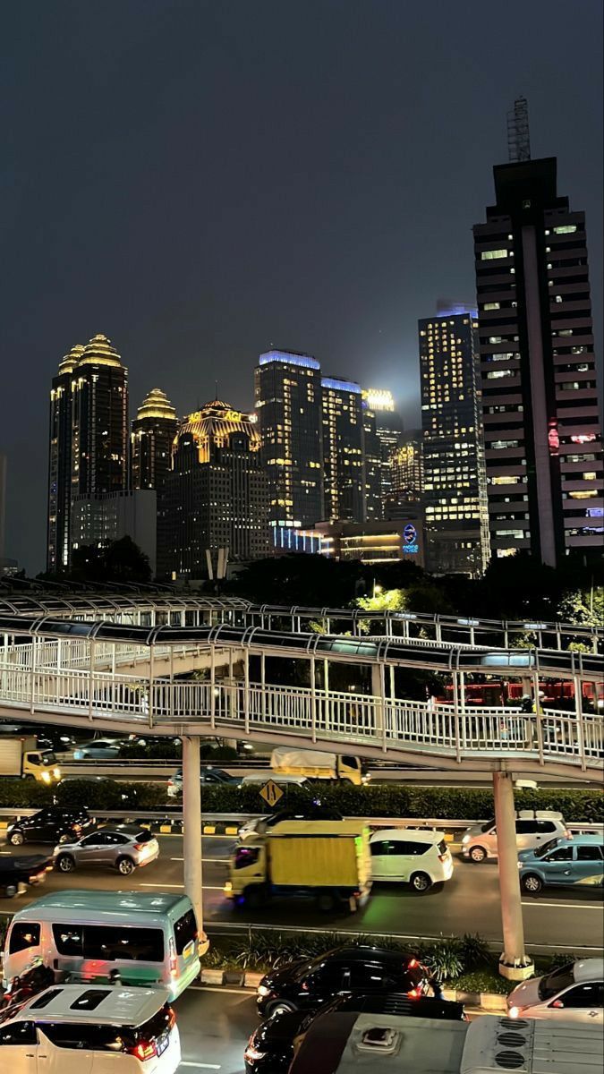 the city skyline is lit up at night, with cars driving on the road below