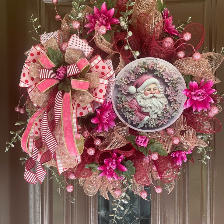 a wreath decorated with pink flowers and a santa clause on the front door for christmas