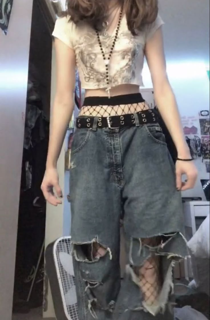 a woman standing in front of a mirror wearing high waisted jeans and a crop top