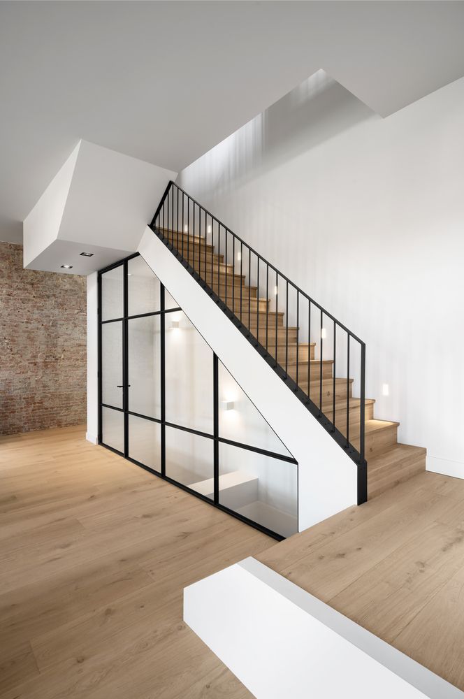 an empty room with wooden floors and white walls, stairs leading up to the second floor