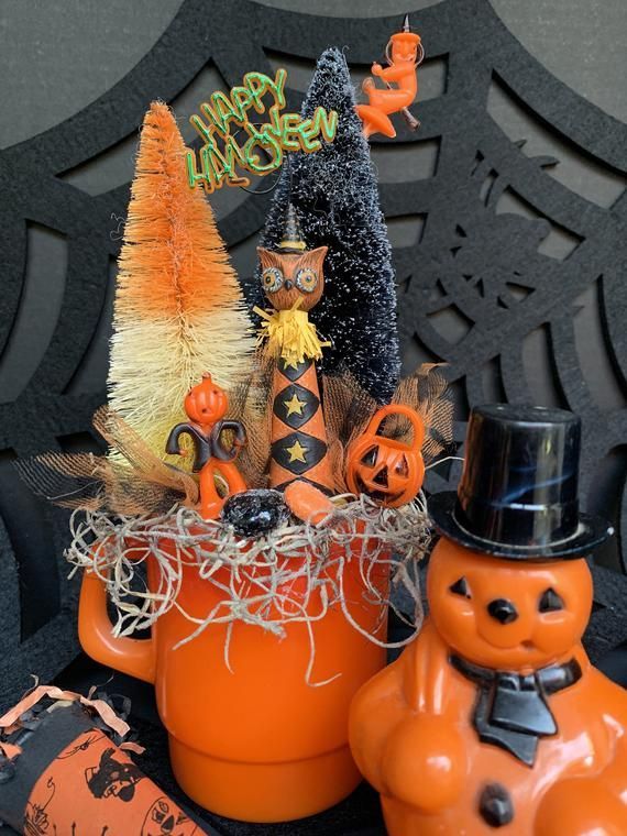 an orange vase filled with halloween decorations on top of a table