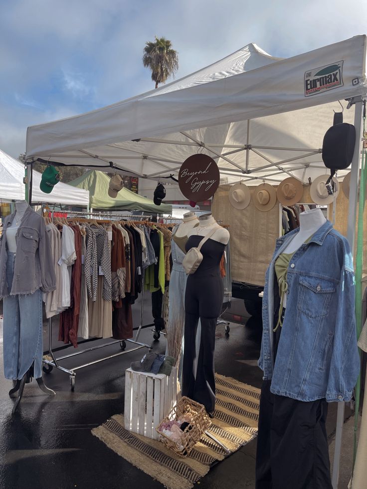 an outdoor market with clothes on display under a tent