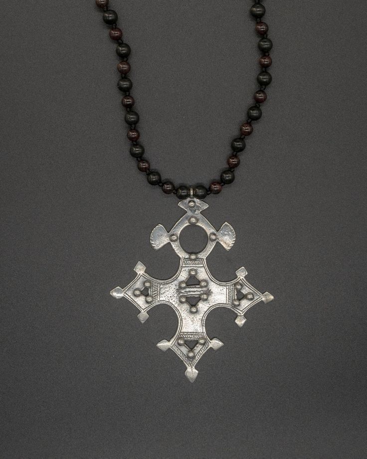 This unique pendant captures the essence of the traditional Tuareg design. Nomads of the desert, the Tuareg inhabit a vast territory spanning from the Moroccan Saharan desert to Burkina Faso in the south. This silver Nigerian Tuareg Bartchakea cross is paired with a hand-knotted shungite and garnet chain. The shungite & garnet chain is 73 cm long [28.75 in long] Traditional Necklace With Large Cross Pendant, Traditional Cross Pendant Necklace With Large Pendant, Traditional Cross Pendant For Ceremonial Occasions, Traditional Cross Necklace With Large Pendant, Unique Pendant, The Desert, Healing Stones, The South, Handcrafted Jewelry